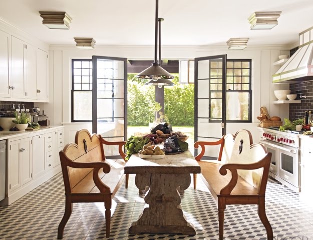 Eat in kitchen by Steven Gambrel with outdoor benches surrounding a 19th Century oak table, pendant lights and a grey and white prism tile floor