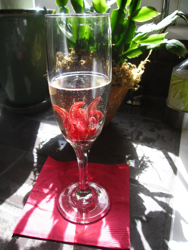  Glass of champagne with dark rose colored edible Wild Hibiscus flowers at a Baby Shower
