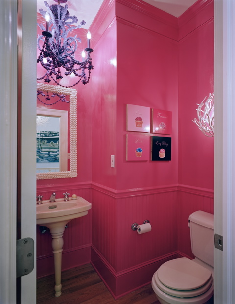 Small hot pink bathroom in a Beach House in New York by Ghislaine Vinas with mirror with a shell trim, chandelier and a pedestal sink