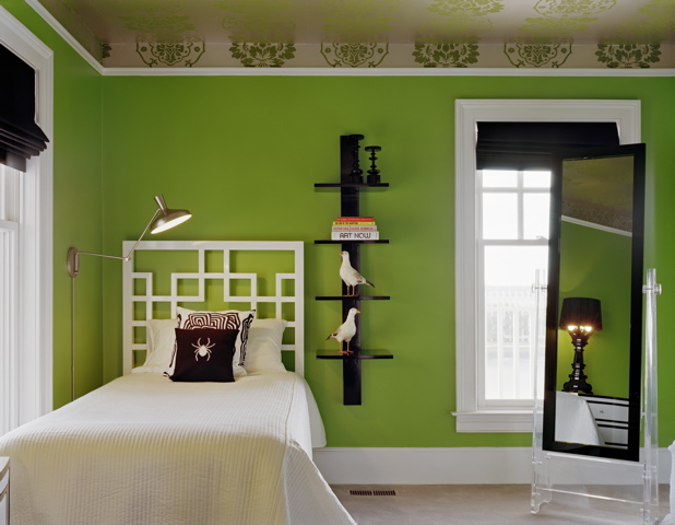 Guestroom at a beach house in New York by Ghislaine Vinas with kelly green walls, white trim, green and white brocade wallpaper on the ceiling, black accessories, and a graphic white lacquer headboard 