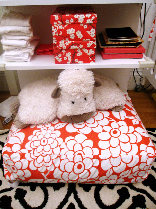 Cute white cow on a pink and white floral floor pillow in a nursery in an NYC loft with custom storage boxes