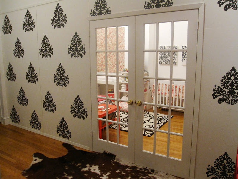 Entry way outside a nursery with dark grey medallion brocade wall decals, French doors and a cowhide rug