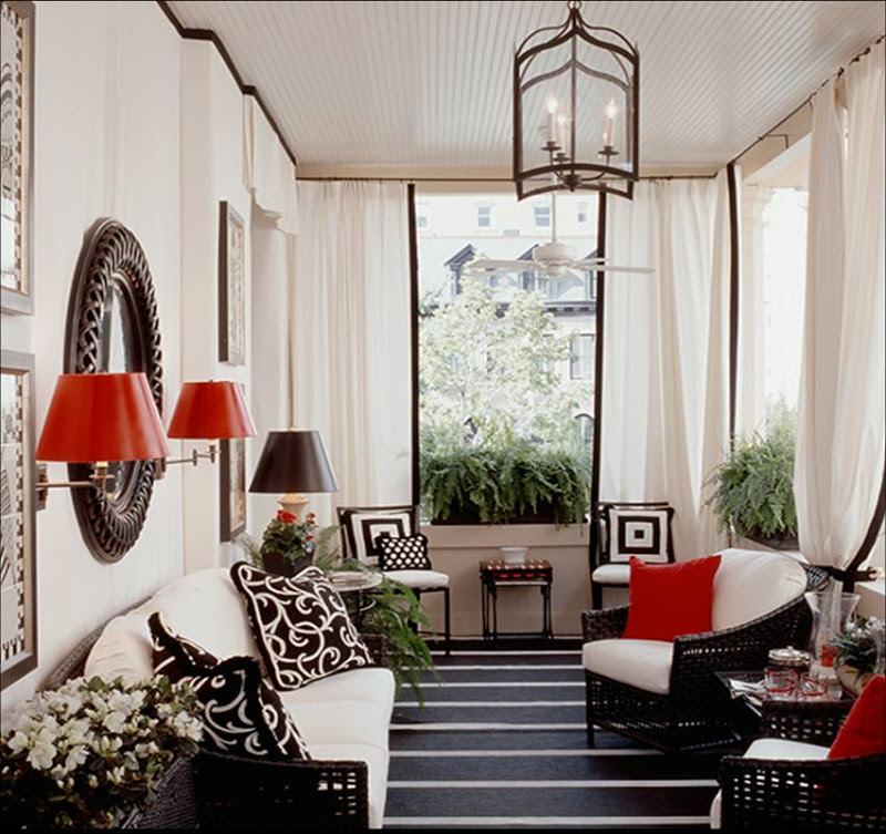 Black and white sun room by Kelley Proxmire with striped floor, beadboard ceiling, white drapes with black trim, white walls, black wicker armchairs and sofa and red accent pillows