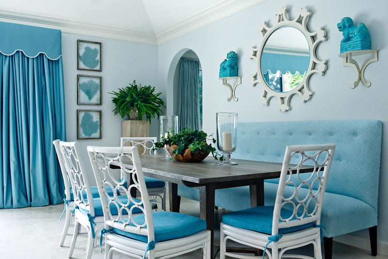 Blue dining room with white lacquer rattan chairs with a circle patterned back and bench seating