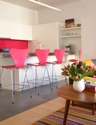 Open kitchen with pink barstools and a hot pink backsplash 