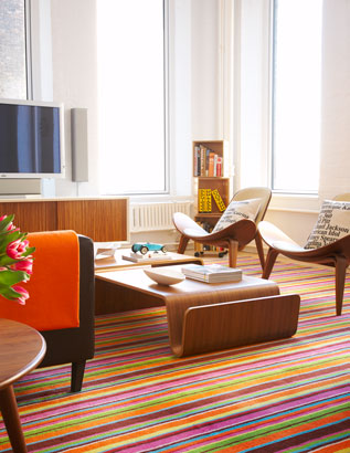 Living room with brightly colored striped rug and leather chair with typographic accent pillows