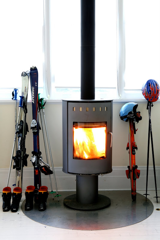 Freestanding fireplace in a living room by Robert and Cortney Novogratz surrounded by ski gear