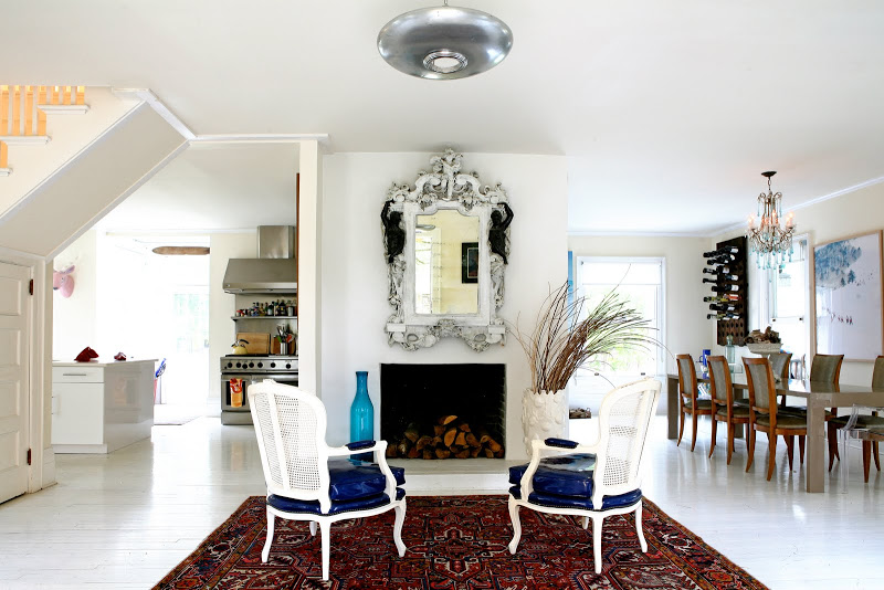 Formal living room by Robert and Cortney Novogratz with a Persian rug, white lacquer fauteuils in front of a fireplace with a large venetian glass mirror