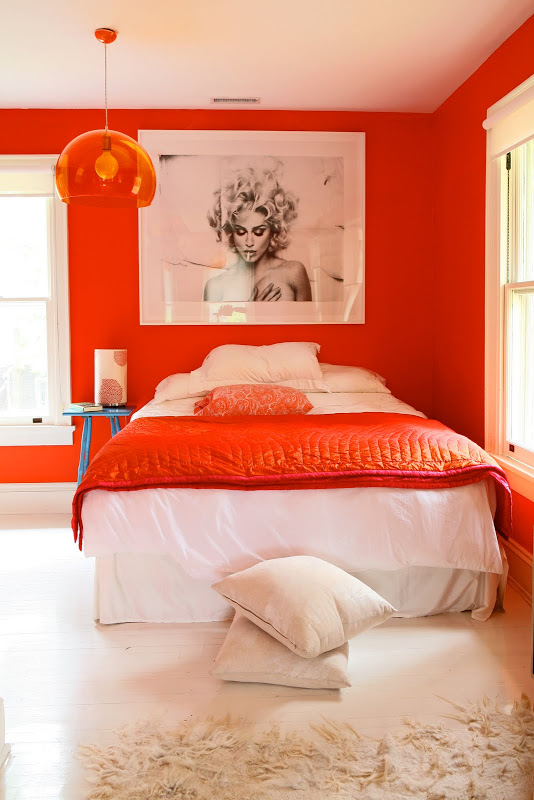 Bright orange walls in a bedroom by Robert and Cortney Novogratz with matching pendant light