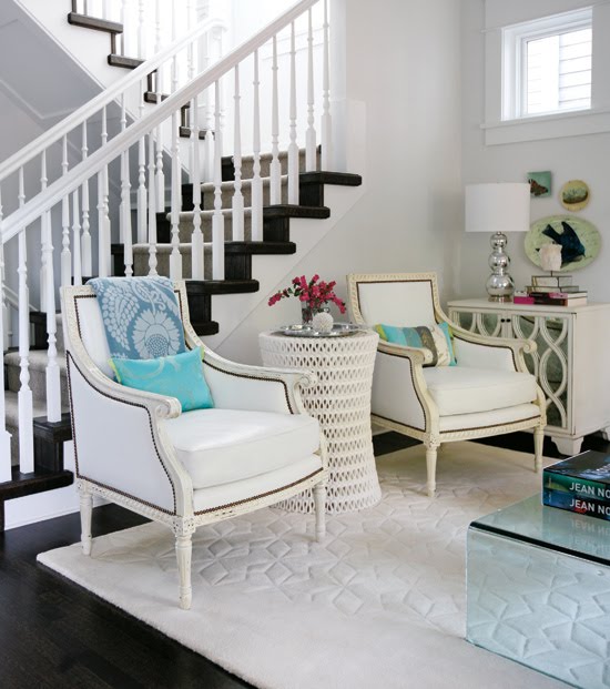 Modern meets traditional in a light airy living room with white Louis XIV armchairs and a white woven sidetable