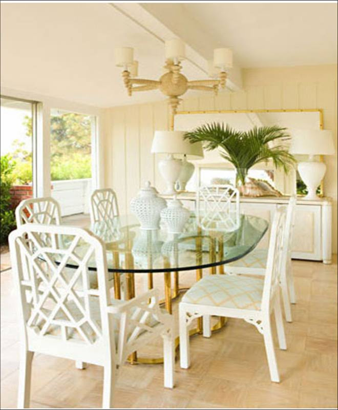 Dining room by Kristen Hutchins with glass table with a brass base surrounded by white lacquer chairs