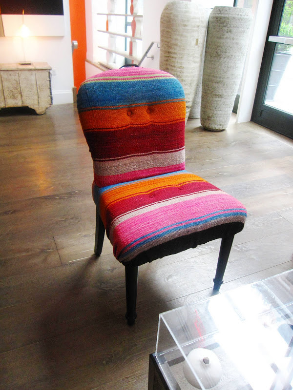 Chair with a curved back and spindle legs upholstered in a Mexican blanket like fabric in the Crosby Street Hotel