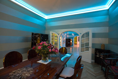 Dining room with a long wood table, painted striped walls and mood lighting