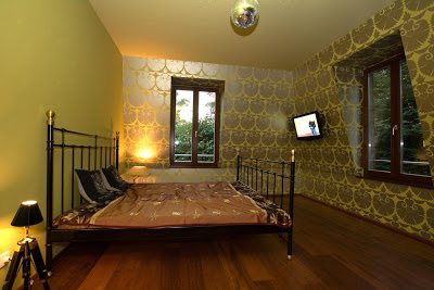 Bedroom in a hamburg home with black iron bed frame, wood floor and graphic wall paper on two walls