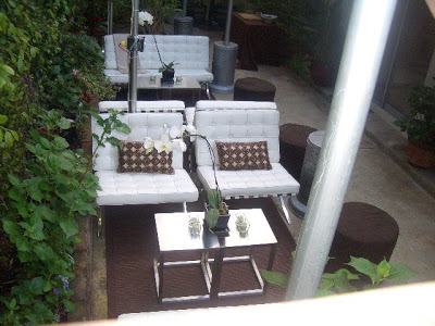 Outdoor patio with white Barcelona inspired chairs and sofa, heat lamps, orchids and metal side tables