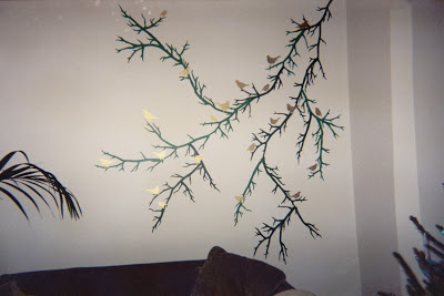 Mural with gold birds sitting on a green branch in a London flat