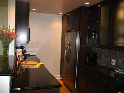Small kitchen after remodeling with stainless appliances, black counter tops and cabinets