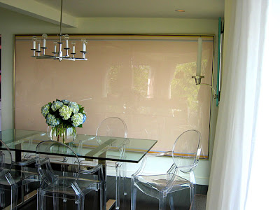 Dining room by M. Design Interiors with a glass table, Philippe Starck Ghost Louis Chairs and a modern chandelier