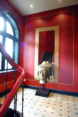 Red stairwell with tile landing, large mirror and a Buddha head