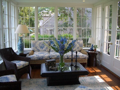 Sitting area in a Nantucket sunroom with rattan armchairs and sofa with cream and blue floral cushions