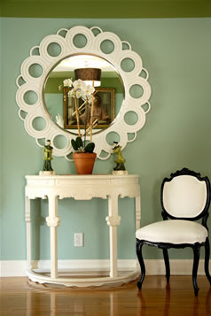 Hand carved and painted round white mirror from Wandrlust in an foyer