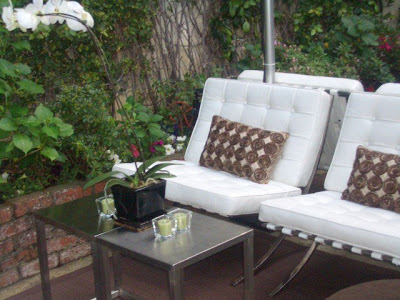Outdoor patio with white Barcelona inspired chairs, orchids and metal side tables