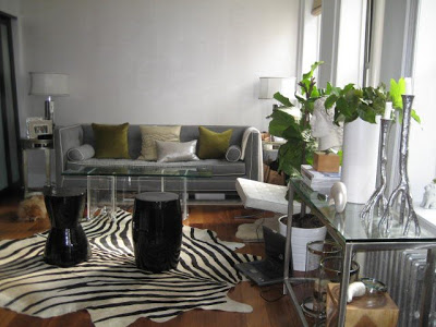 Living room with a Jonathan Adler sofa, two black Chinese garden stools, a zebra print and glass coffee table