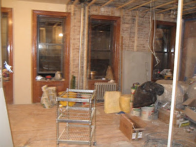 Living room with tall windows and exposed brick before remodeling