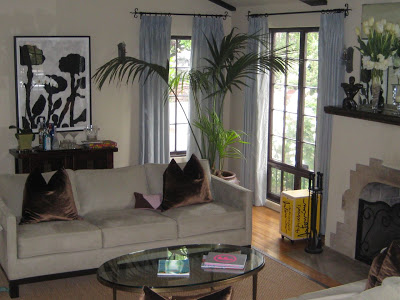 Living room in the Nugent's home with Donald Baechler's Untitled (Cast Flowers) on the wall, grey sofa, wood floor and a potted palm