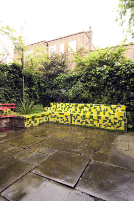 London garden with a green and yellow mosaic bench and fountain