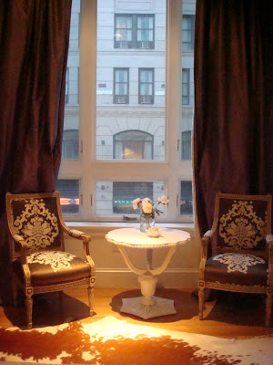 Sitting area in a NYC loft with antique chairs upholstered in Silk Trading Co. fabic, a white cow hid rug, white antique table and long silk purple curtains