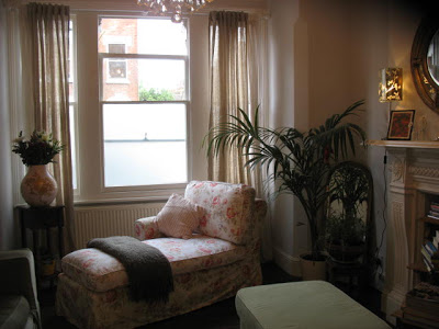 Living room in a London flat with a floral upholstered chaise lounge under a window