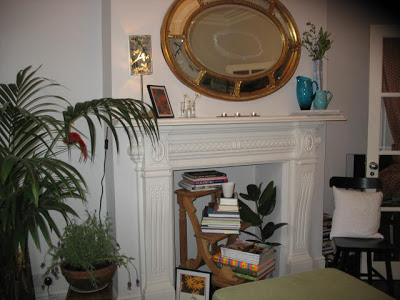 Living room in a London flat with traditional mantel and a non-working fireplace with a small step stool doubling as a bookshelf