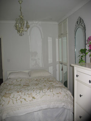 White bedroom in a London flat with a white chandelier 