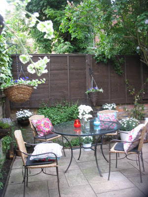 Private garden patio with a wrought island table and chairs with floral pillows