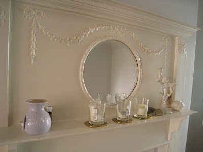 Decorated mantelpiece with an arrangement of candles, vases and a ceramic tree limb