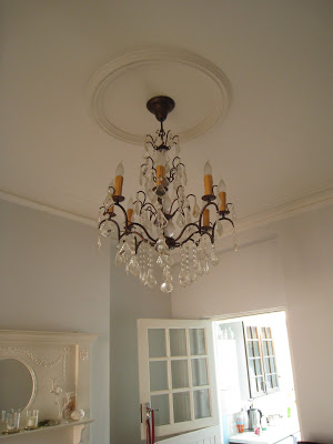 Dining room in a London flat with a crystal chandelier hanging from a simple ceiling medallion
