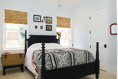 Bedroom in an Alys Beach home with bamboo roll up shades, black four poster bed, and a basket doubling as a side table