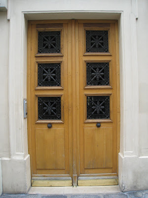 Light natural wood stain door on Rue de Seine with intricate wrought iron panes