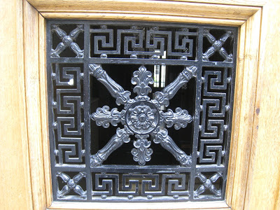 Close up of the intricate wrought iron panes on light natural wood stain door on Rue de Seine