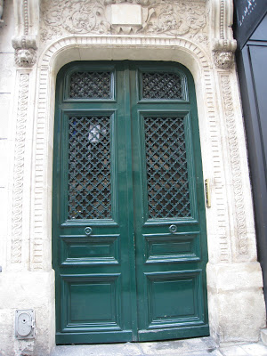 A hunter green door with a carved stone door casing