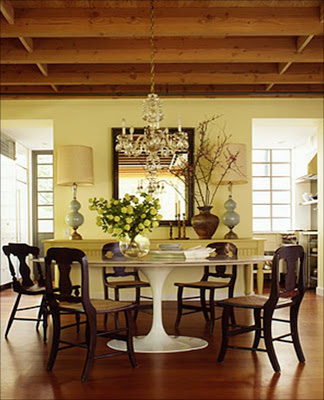 Dining room with retro Saairnen table, dark wood chairs, crystal chandelier and yellow walls