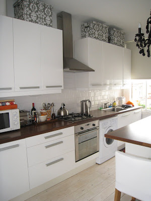 Glossy white Ikea cabinets and butcher block wood counters in a London kitchen