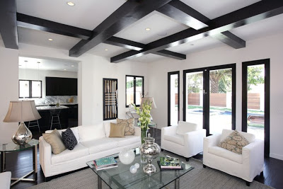 Black and white living room with painted black exposed beams, a white sofa and two large comfy white armchairs