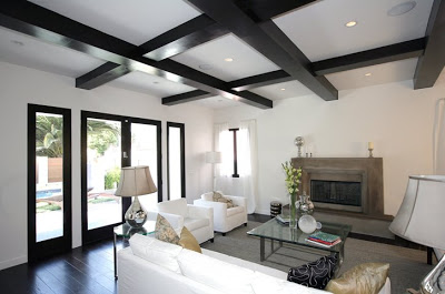 Black and white living room with painted black exposed beams, a white sofa and two large comfy white armchairs