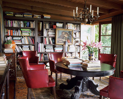 Library with dark wood pedestal table, red leather chairs and dark wood built in bookcases