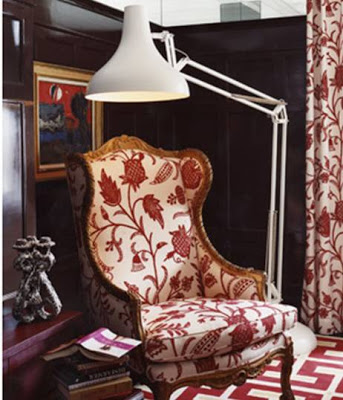 Classic wing back chair upholstered in red and white floral pattern in a home library