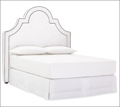 Tall white upholstered headboard with curves and arches from Pottery Barn