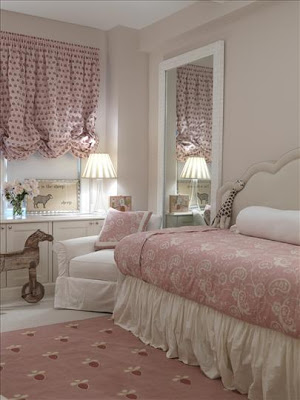 Pink and white nursery with a daybed with an upholstered headboard and paisley printed duvet and a wooden rocking horse