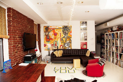 Living room in an NYC director and dj's home featured on The Selby with an exposed brick wall and the phrase "Love You" written on the floo